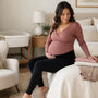 Pregnant woman wearing a comfortable nursing top and maternity leggings in a calm bedroom
