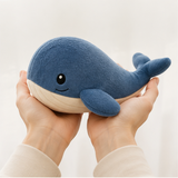 Adult hands holding the 25 cm blue whale plush for scale