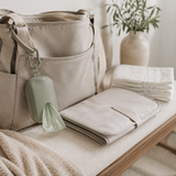 Sage diaper disposal bag dispenser clipped to a diaper bag