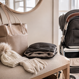 Folded stroller hand muff with winter accessories on an entry bench