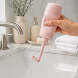 Blush pink postpartum peri rinse bottle held over a clean bathroom sink
