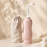 Blush pink upside-down peri rinse bottle with angled nozzle and travel pouch