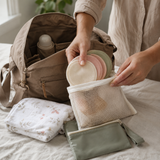 Reusable nursing pads packed into a mesh pouch beside a diaper bag