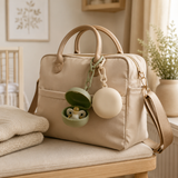 Pacifier cases clipped to the handle of a neutral diaper bag