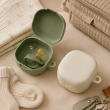 Sage and cream pacifier cases arranged with diaper bag essentials