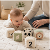 Baby playing with soft sensory cubes under adult supervision