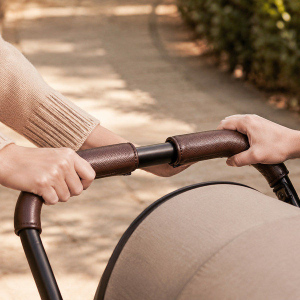 Adult hands holding cocoa grip covers on a stroller handlebar
